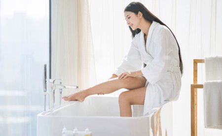 Woman applying cream on her body