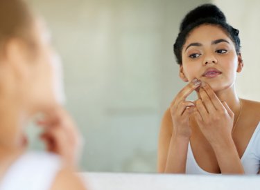 Woman with acne-prone skin looking in a mirror